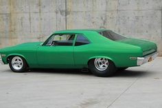 a green car parked in front of a concrete wall