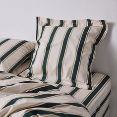 an unmade bed with green and white striped sheets