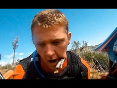 a man in an orange vest eating something off of his mouth while standing on the ground