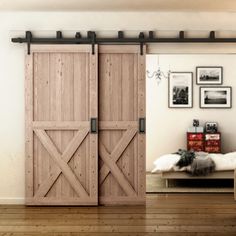 an open sliding barn door in a living room with hardwood flooring and pictures on the wall