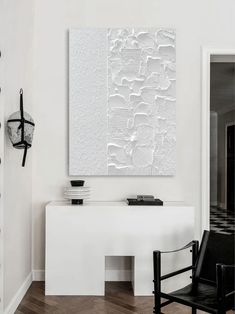 a white room with black chairs and a large piece of art hanging on the wall