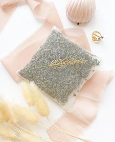 a small bag filled with green tea next to some feathers and other items on a white surface