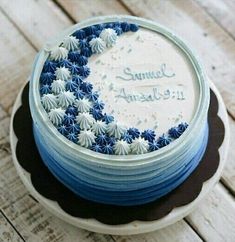 a blue and white cake sitting on top of a wooden table covered in frosting