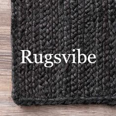 the word rugsvibe written in white on a black bath mat with wood background