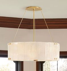 a chandelier hanging from the ceiling in a living room with large windows and wood trimmings