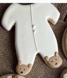 decorated cookies are arranged in the shape of baby's feet and onesuits