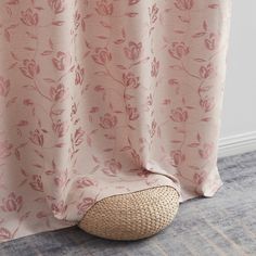 a pink flowered curtain hanging on the side of a wall next to a basket