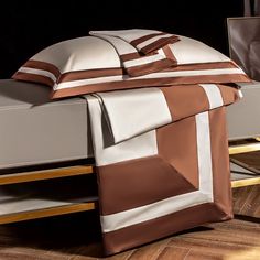 a bed with brown and white sheets on top of it next to a night stand