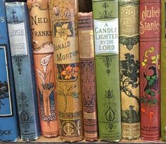 a row of books sitting on top of a book shelf filled with lots of different colored books