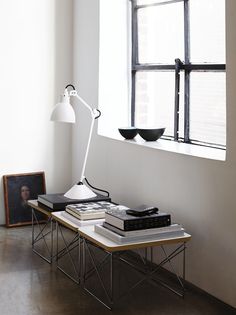 a table with two books and a lamp on it in front of a large window