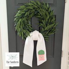 a wreath on the front door with a white scarf hanging from it's side