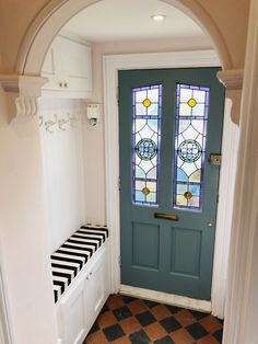 a blue door with a bench in front of it and a stained glass window above