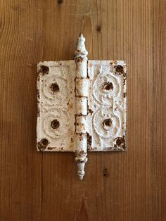 an old white door handle on a wooden wall with peeling paint and holes in it