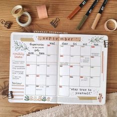 an open planner sitting on top of a wooden table next to other office supplies and accessories