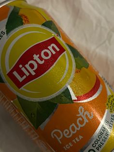 a can of lipton peach tea sitting on top of a white cloth covered table