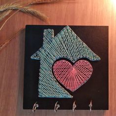 there is a small piece of string art with a house and heart in the middle