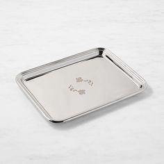 a square metal tray with paw prints on the front and bottom, sitting on a marble surface