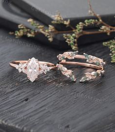 two wedding rings on top of a wooden table with greenery in the back ground