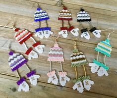 knitted christmas ornaments are arranged on a wooden table with string and beads hanging from them