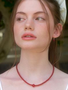 a woman wearing a white hat and red beaded necklace