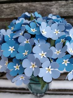 a vase filled with blue flowers sitting on top of a wooden bench