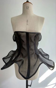 a mannequin wearing a black corset with sheer fabric