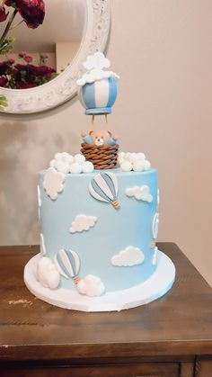 a blue and white cake with hot air balloons on top