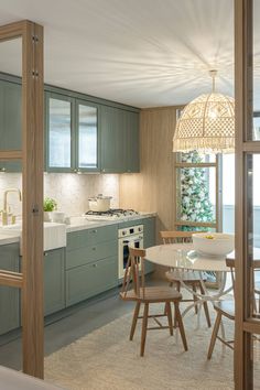 a kitchen with green cabinets and white counter tops next to a dining room table that has chairs around it