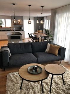 a living room filled with furniture next to a kitchen and dining room table on top of a shaggy rug