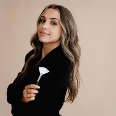 a woman with long hair wearing a black top and holding a white spoon in her hand