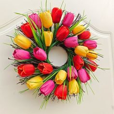 a wreath made out of colorful tulips on a white wall