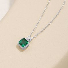 This exquisite pendant necklace showcases a brilliant emerald in a classic solitaire setting, radiating a lush green hue. Its elegant simplicity makes it a standout piece, perfect for enhancing any neckline with a touch of refined sophistication. Green Emerald Diamond Pendant Necklace, Elegant Emerald Pendant Necklace With Clavicle Chain, Green Diamond Necklace Fine Jewelry, Fine Jewelry Green Diamond Necklace, Elegant Emerald Necklace With Round Pendant, Elegant Emerald Round Pendant Necklace, Elegant Emerald Birthstone Necklace With Round Pendant, Elegant Green Solitaire Necklace For May Birthstone, Classic Green Emerald Necklace With Bezel Setting