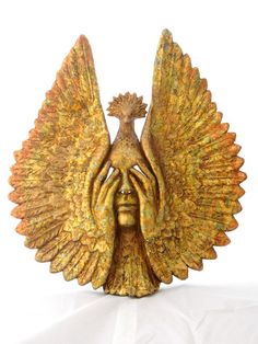 a golden statue with an outstretched hand holding it's face in front of its head