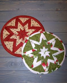 two circular quilts sitting next to each other on a wooden surface with wood boards behind them