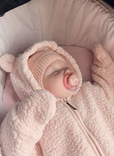 a baby sleeping in a pink blanket with a pacifier