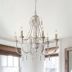 a white chandelier hanging from the ceiling in a room with windows and curtains