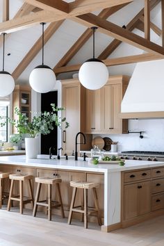 a large kitchen with wooden beams and white counter tops, two stools at the island