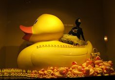 a large yellow rubber duck sitting on top of a pile of baby ducks in a display case