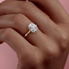 a woman's hand holding an engagement ring with a diamond in the center and a twisted band around it