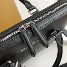 a black purse with two zippers on the front and one in the back, sitting on top of a table