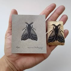 a hand holding a stamp with a moth on it