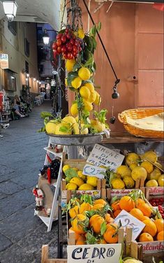 a fruit stand on the side of a street with oranges, lemons and other fruits