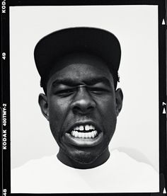 a black and white photo of a man wearing a baseball cap with his mouth open