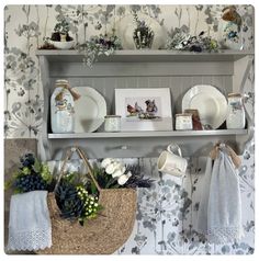 a shelf filled with dishes and vases on top of a wall next to flowers