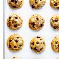 twelve chocolate chip cookies arranged in rows on a baking sheet, ready to be baked