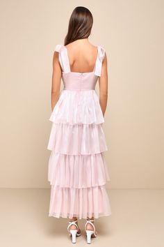 the back of a woman wearing a pink dress with tiered layers and white shoes