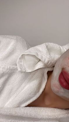 a woman laying in bed with a white sheet on her head and wearing a face mask