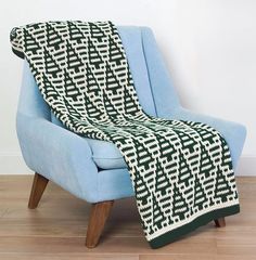 a blue chair with a black and white knitted blanket on it's back