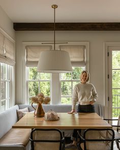 a woman standing in front of a wooden table