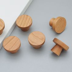 three wooden knobs and two round knobs on a gray surface